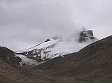 Tibet Kailash 09 Kora 04 Last Cloudy View of Kailash Across the valley, a trail branches off to the southeast over the snow-covered Khandro Sanglam La, the Secret Path of the Dakini Khandroma). This alterative route around Kailash bypasses the Dlma La, which tradition says can only be crossed if you have completed 12 previous koras.